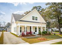 Charming home featuring a welcoming front porch, light siding, and well-manicured landscaping at 100 Pine Waters Ln, Summerville, SC 29483