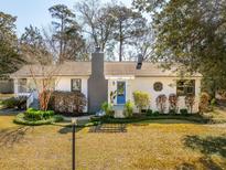 Charming white brick home with a blue front door, well-maintained landscaping and a gray chimney at 1245 Forestwood Dr, Charleston, SC 29407