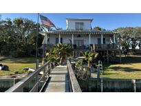 Inviting elevated beach house featuring a private dock, solar panels, and charming architectural details at 3113 Buccaneer Rd, Isle of Palms, SC 29451