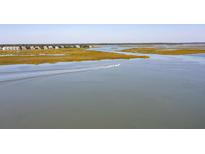 Scenic waterfront view with a boat on the water with neighborhood in the background at 410 E Indian Ave, Folly Beach, SC 29439