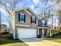Charming two-story home features a well-manicured lawn, two car garage and a welcoming covered front porch at 1309 Belgian Draft Dr, Mount Pleasant, SC 29466