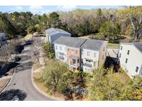 Beautiful aerial view of a multi-story home with manicured landscaping and a serene pond in a lush, wooded neighborhood at 1587 Bluewater Way, Charleston, SC 29414