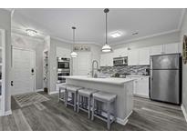 Modern kitchen featuring white cabinetry, stainless steel appliances, and a marble-topped island with barstool seating at 200 Bucksley Ln # 308, Charleston, SC 29492