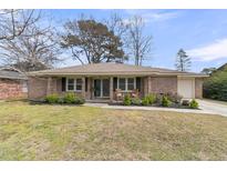 Charming brick home with a well-maintained front yard and a cozy front porch with rocking chairs at 303 Gippy Dr, Summerville, SC 29486