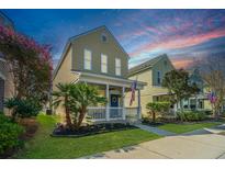 Charming two-story home featuring a cozy front porch, well-manicured lawn, and blooming flowers creating a welcoming curb appeal at 425 Verbena Ave, Summerville, SC 29483