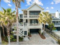 Stunning three-story beach house with multiple balconies, palm trees, and a brick driveway at 707 Ocean Blvd, Isle of Palms, SC 29451