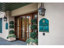 Elegant building entrance featuring wooden doors, manicured greenery, and decorative lighting fixtures at 1 Vendue Range # D, Charleston, SC 29401