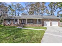 Charming brick home featuring a well-manicured lawn, attached two-car garage and covered front porch at 104 Wessex Ter, Summerville, SC 29485