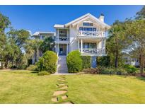 Stunning two-story white home with dual balconies, grand staircase, and lush lawn at 1302 Middle St, Sullivans Island, SC 29482
