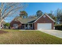 Charming brick home featuring a manicured lawn, covered porch, and attached two-car garage at 1633 Wayah Dr, Charleston, SC 29414