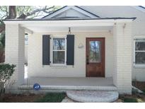Charming front porch with a brick trim, a wooden front door, and an ADT security system sign for added peace of mind at 1637 Tatum St, Charleston, SC 29412