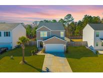 Charming two-story home with a well-maintained lawn and beautiful landscaping with a palm tree at sunset at 206 Cypress Plantation Rd, Moncks Corner, SC 29461