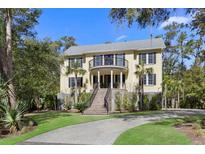 Stately two-story home boasts a charming front porch, upper balcony, and lush landscaping at 2440 Cat Tail Pond Rd, Seabrook Island, SC 29455