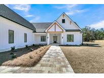 Charming exterior view of a modern farmhouse with a stone walkway and manicured landscaping at 4036 Azalea Farms Way, McClellanville, SC 29458