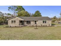 Charming brick home with a well-manicured lawn and mature trees against a clear blue sky at 5330 Waterview Dr, North Charleston, SC 29418
