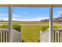 Inviting porch view reveals expansive grassy front yard and a picturesque landscape at 729 2Nd Bend Rd, Harleyville, SC 29448