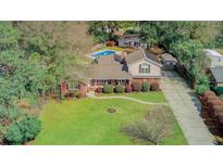 Stunning aerial view of a brick home with lush lawn, mature trees, and a sparkling pool, offering a private and serene oasis at 958 Mikell Dr, Charleston, SC 29412