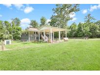 Sprawling property with a covered outdoor area, surrounded by lush greenery and a fenced yard at 13959 Cottageville Hwy, Cottageville, SC 29435