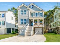 Charming two-story home features a welcoming porch, double garages, and manicured front yard at 312 Coki Amalie Ct, Charleston, SC 29492