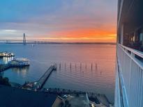 Stunning water view featuring a distant bridge and boat, all under a vibrant, colorful sunset sky at 330 Concord St # 11D, Charleston, SC 29401
