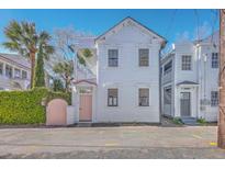 Charming white two-story home featuring a pink door, lush landscaping, and a balcony at 10 Humphrey Ct, Charleston, SC 29403
