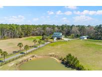 Expansive property featuring a charming two-story home, pond, and lush greenery from an aerial perspective at 1008 Hoodtown Rd, Bonneau, SC 29431