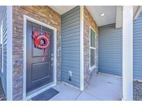 Inviting front entry with a black door, stone accents, and an amusing red dragon wreath at 175 Darby Meadow Ln, Ridgeville, SC 29472