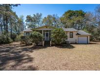 Charming single-story home featuring a screened-in porch and a well-maintained front yard with mature trees at 2104 River Rd, Johns Island, SC 29455