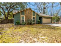 Charming home featuring green siding, stone accents, well-maintained landscaping, and an attached garage at 2306 Chairmaker Ct, Charleston, SC 29414