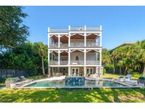 Stunning three-story home featuring a refreshing pool with water feature and multiple outdoor seating areas at 3006 Cameron Blvd, Isle of Palms, SC 29451