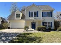 Charming two-story home featuring a two-car garage, manicured lawn, and bright blue shutters at 329 Carriage Wheel Rd, Moncks Corner, SC 29461