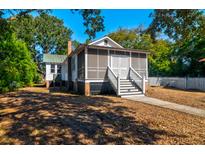 Charming single-story home with a screened-in porch and white picket fence, surrounded by lush greenery at 2314 Goldbug Ave, Sullivans Island, SC 29482