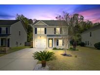 Charming two-story home with a well-manicured lawn and driveway at dusk at 236 Emerald Isle Dr, Moncks Corner, SC 29461