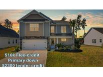 Charming two-story home with a manicured lawn and a two-car garage during a lovely sunset at 261 Celestial Blvd, Summerville, SC 29486