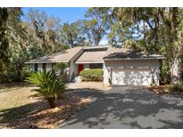 Charming single-story home featuring a red door, garage, and lush landscaping at 3475 Deer Run Rd, Seabrook Island, SC 29455