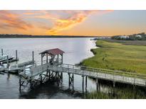 A wooden dock with a covered gazebo extends into the water at sunset, offering scenic waterfront views at 4247 Faber Place Dr # 5103, North Charleston, SC 29405