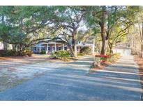 Charming brick home featuring a welcoming front porch and beautifully landscaped yard with mature trees at 10812 Dorchester Rd, Summerville, SC 29485