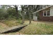 Charming brick home featuring a wooden bridge and arbor in a natural, wooded setting at 2231 Burris Rd, Charleston, SC 29414