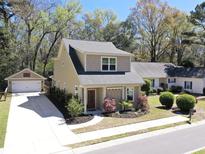 Charming two-story home with well-manicured lawn, red door, and detached garage with basketball hoop at 263 Stefan Dr, Charleston, SC 29412
