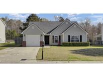 Charming single-story home with gray siding, attached garage, and well-maintained lawn at 306 Slow Mill Dr, Goose Creek, SC 29445