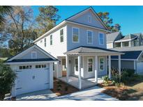 Charming two-story home with a detached garage, landscaped yard, and inviting front porch at 3285 Johnstowne St, Johns Island, SC 29455