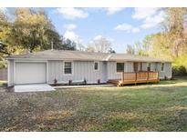 Charming single-story home with light gray siding, a front deck, and a manicured lawn with updated landscaping at 1174 Fort Johnson Rd, James Island, SC 29412