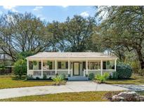 Charming single-story home with a welcoming front porch, landscaped yard, and mature trees at 1515 Devons St, Charleston, SC 29412