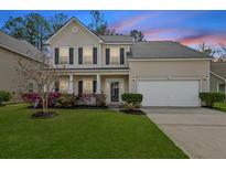 Charming two-story home featuring a well-manicured lawn, flowering bushes, and an attached two-car garage at 184 Charlesfort Way, Moncks Corner, SC 29461