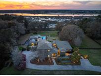 Stunning aerial view of estate home with river access, manicured landscaping, and a private pool at sunset at 4020 Betsy Kerrison Pkwy, Johns Island, SC 29455