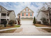 Charming two-story home with a well-manicured lawn and a two car garage with red shutters and beige colored siding at 2049 Maybelles Ln, Charleston, SC 29414