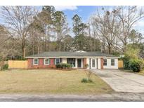 Charming one-story home with a red brick and white exterior, complemented by a well-manicured lawn and mature trees at 211 Logan Dr, Summerville, SC 29483