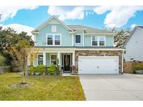 Charming two-story home with a light blue exterior, stone accents, manicured lawn and a two-car garage at 2165 Annie Laura Ln, Mount Pleasant, SC 29466