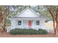 Charming cottage-style house with a porch, coral front door, and white exterior at 3166 Edenvale Rd, Johns Island, SC 29455