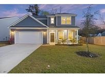 Charming two-story home with a well-manicured lawn, attached garage, and classic architectural details at dusk at 3215 Safe Harbor Way, Charleston, SC 29414